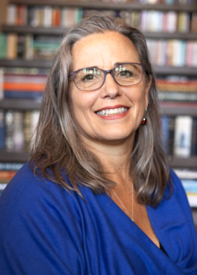 SMith women with light and dark gray hair. Wearing a blue shirt and glasses